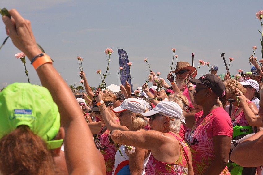 Sarasota International Dragon Boat Festival participants held flowers aloft as part of a ceremony honoring paddlers diagnosed with breast cancer. The flowers were then tossed into the water.