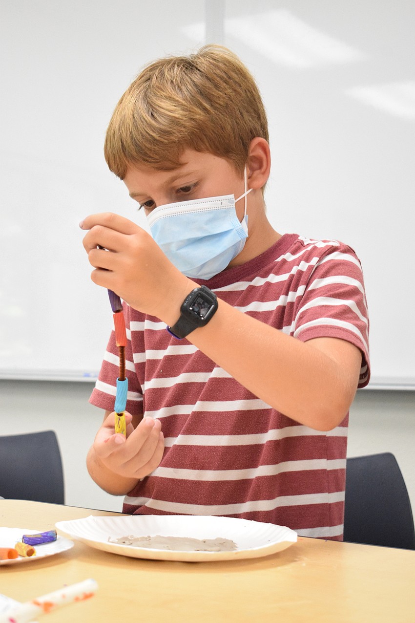 Blake Rattigan piles painted noodles onto a pipe cleaner to start assembling his coral reef.