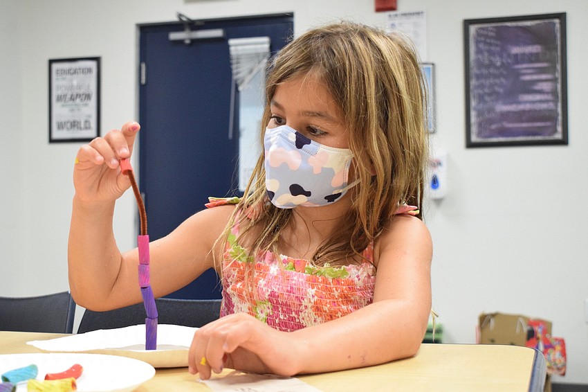 Emme Schweitzer adds painted noodles to a pipe cleaner before curving it to make it into coral.