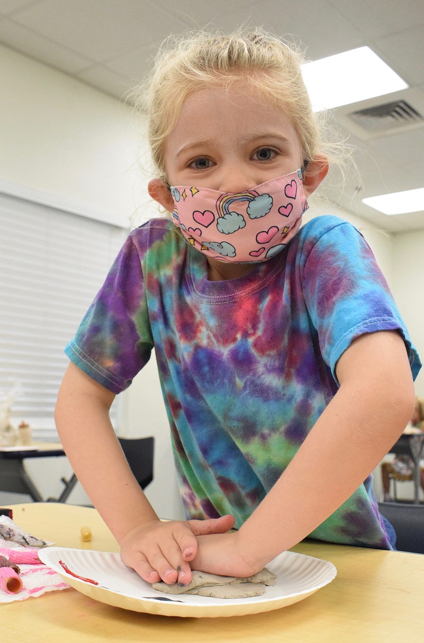 Margaret Athas puts all her strength into smashing clay onto her plate as a base for her coral reef.