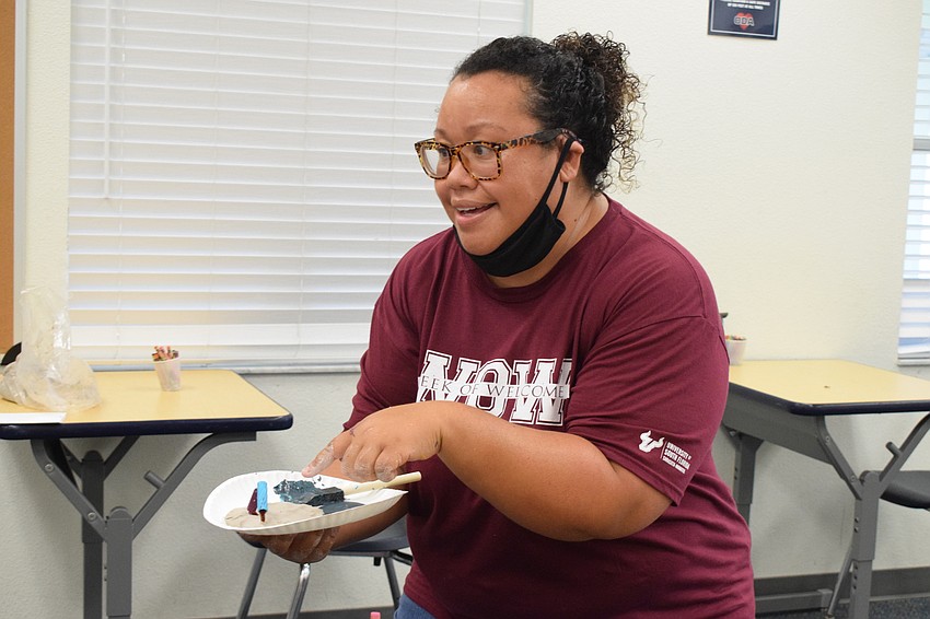 Melissa Mayoral, a leader of Camp Banyan, shows a group of kindergartners what their coral reefs will start to look like as they begin assembling their noodles and pipe cleaners.