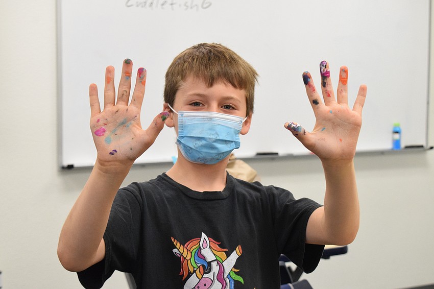Oliver Valenti shows off his multi-colored hands while painting noodles for his coral reef.