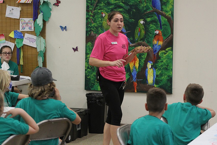 Education Coordinator Britney Webb shows Potato the bearded dragon to the camp.