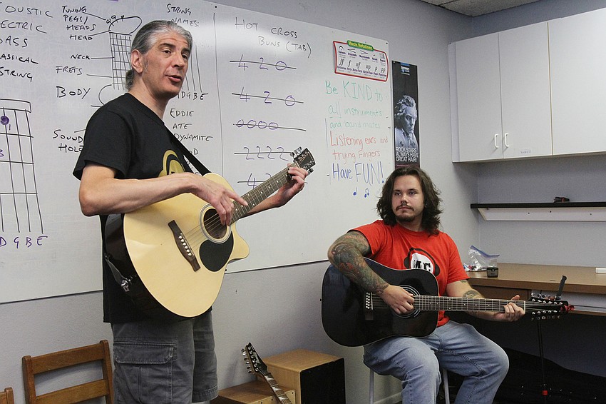Instructors Iain Harris and Timothy Updegraph teach guitar to campers.