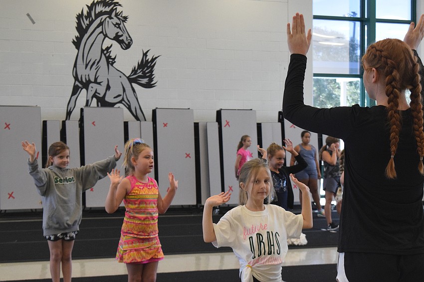 Austin Conner, who is 7, Olivia Goetsch, who is 6, and Bristol Scott, who is 7, cheer for Lakewood Ranch High School mustangs along with JV cheerleader Kendall Crowell.