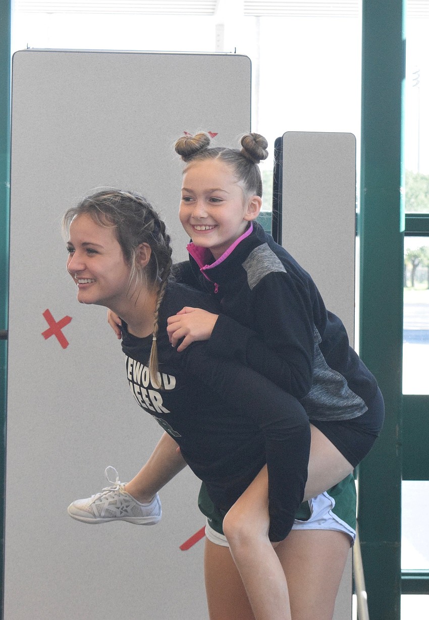 Lakewood Ranch High School JV cheerleader Bridget Coopens carries camper Avionna Twyford on her back during a game.