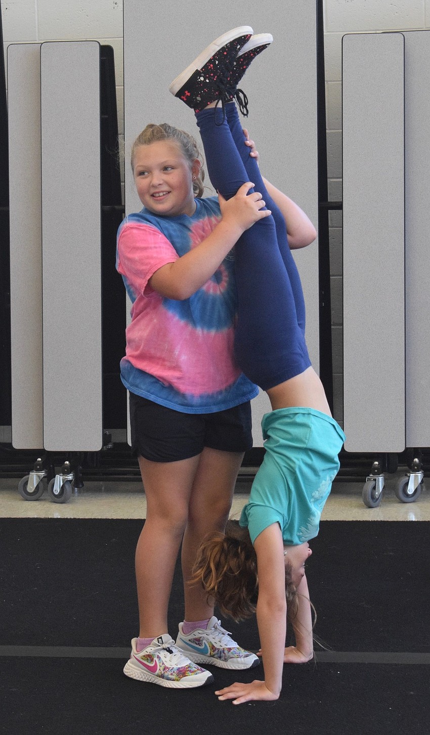 Nahla Vlasak, who is 9, holds 8 year old Ava Clementi's legs while she does a handstand.