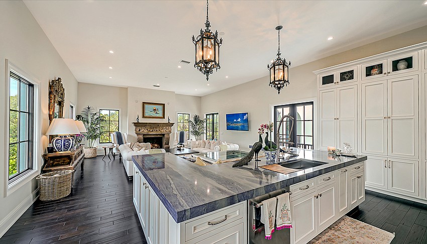 An open kitchen, overlooking the great room, features Blue Azul granite countertops, custom white cabinets, and high-end appliances.