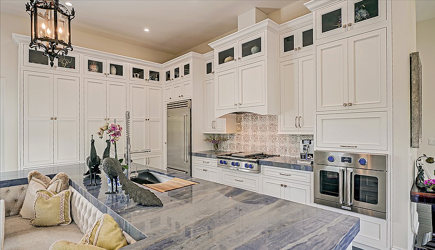 An open kitchen, overlooking the great room, features Blue Azul granite countertops, custom white cabinets, and high-end appliances.