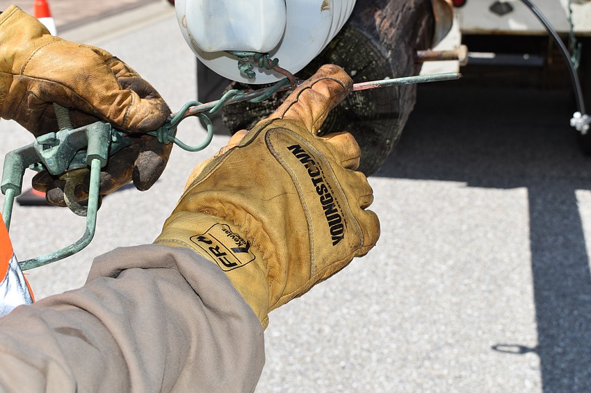 On July 22, Volt Power Co. foreman Jimmy Sasser shows the weathering the copper wires endured on the wooden light poles that workers removed along Birdie Lane.
