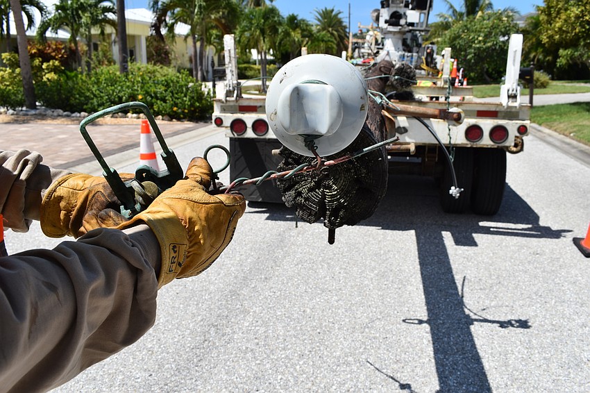 On July 22, Volt Power Co. foreman Jimmy Sasser shows the weathering the copper wires endured on the wooden light poles that workers removed along Birdie Lane.