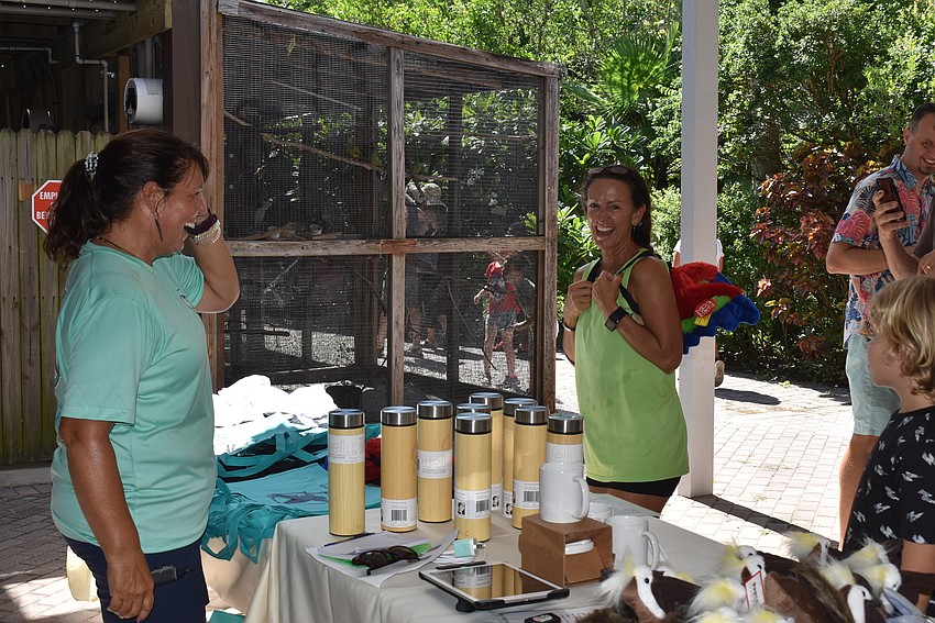 Volunteer Heather Sellers looks on as Stacey Mazza-Gilkison tries on a backpack.