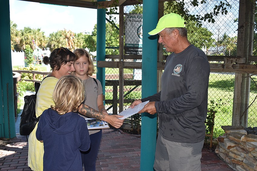 Volunteer Tim Thurman, right, hands out a bird scavenger hunt to Gus, Summer and Lucille Delauro.