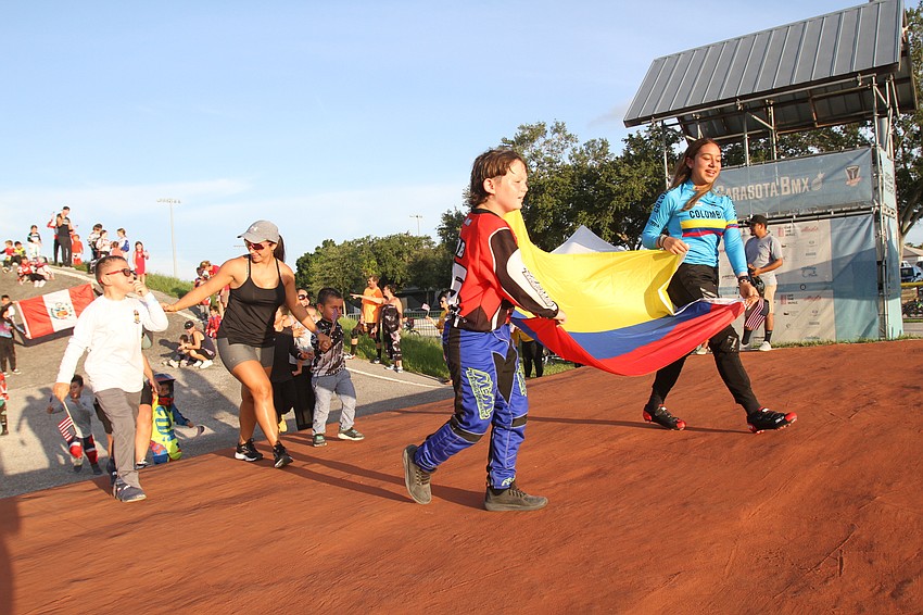 The parade had racers and parents marching with various flags.
