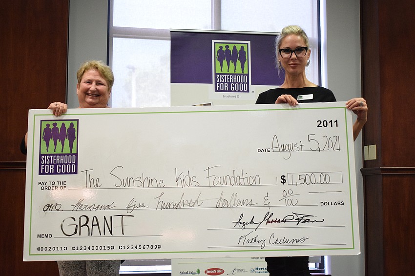 Janet Yon with the Sunshine Kids Foundation accepts a $1,500 grant from Karen Medford, a member of Sisterhood for Good. The grant will benefit 50 to 100 children.