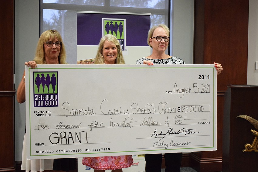 Roxanne Sima with Sisterhood for Good presents a check to Anne Rollings and Kim Noyes with the Sarasota County Sheriff's Office. 