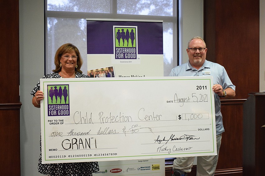 Sisterhood for Good's Laurel Corriveau presents a $1,000 grant to Doug Staley with Child Protection Center. The grant will benefit about 300 children in Child Protection Center's therapy program.