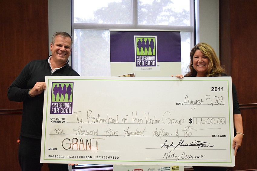 Robert Villanueva, a mentor with the Brotherhood of Men Mentor Group, accepts a grant from Annette Gueli with Sisterhood for Good.