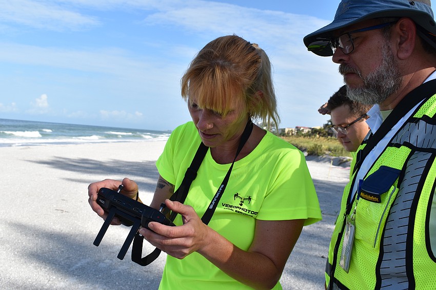 Melissa Matisko watches her screen while flying the DJI Mavic 2 Pro. Hjalmar Pachas (far right) looks on.