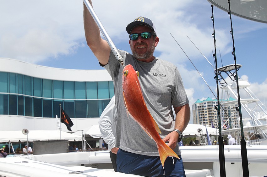 Jack Brown of Off The Hook drops a fish in the container.