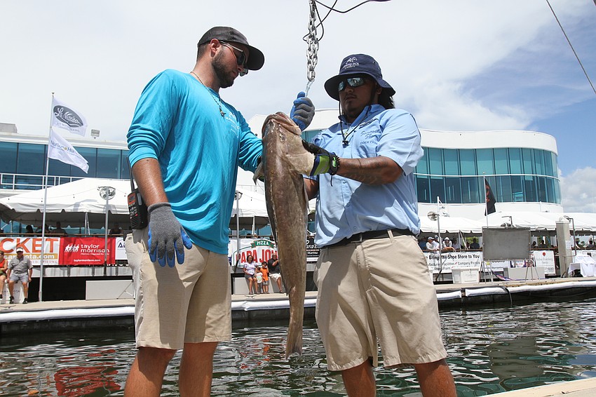 Patrick Lustro and Levi Palacios hook the fish onto the scale.