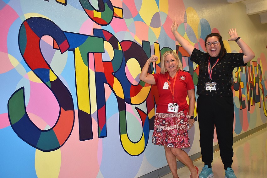 Tara Elementary School music teacher Barbara Siffermann and art teacher Alex Miranda stand by a mural that reads, 