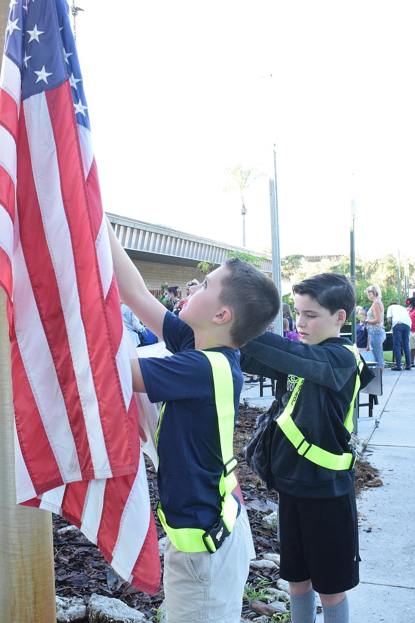 Hunter Dragon and Kason Scarlett, who are fifth graders and safety patrollers at Braden River Elementary School, prepare the flags to be raised outside the school.