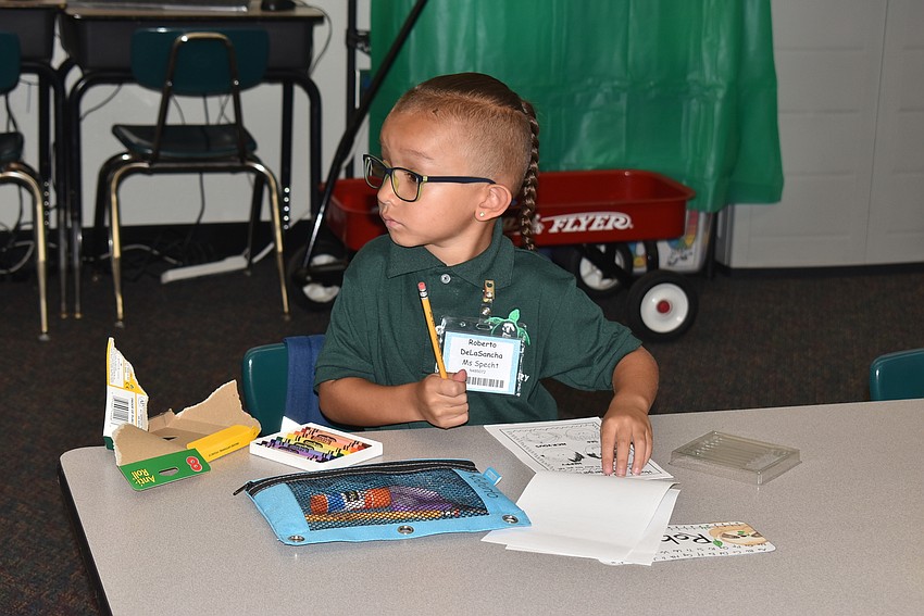 Roberto de la Sancha gets settled into his kindergarten class with his coloring supplies at Tuttle Elementary School.
