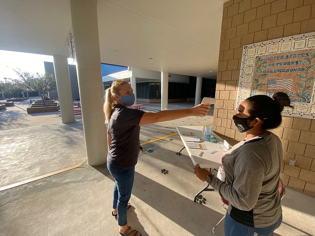 Kristen Cunningham, an assistant principal at Braden River Middle School, checks  Normalinda Faudoa&#39;s temperature. Temperature checks will be taken daily for employees and randomly for students. Courtesy photo.
