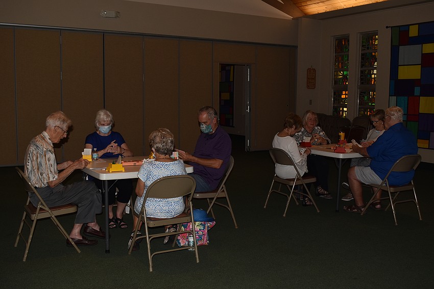 A dozen players grouped together at three tables for their first game.