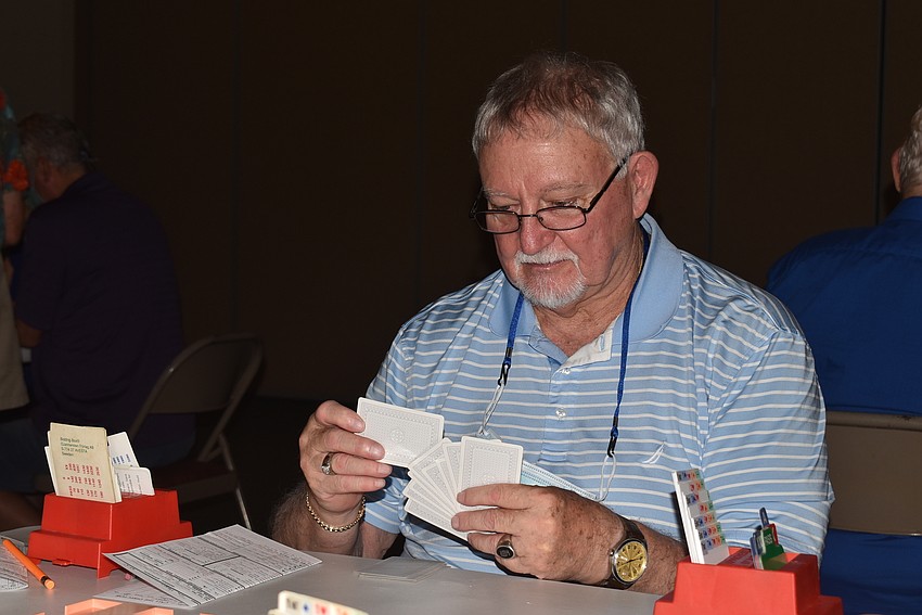 Tom Hagan plays a card in bridge.