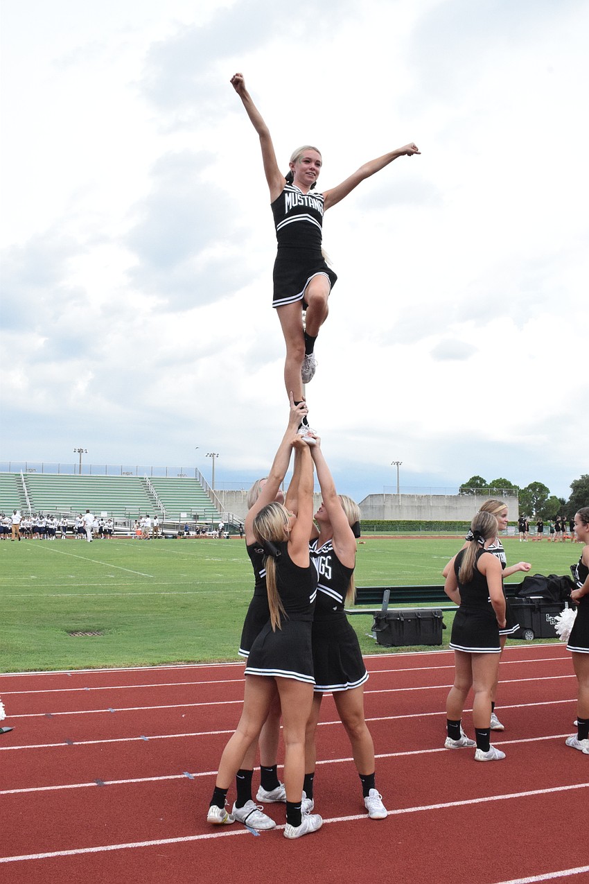 Lakewood Ranch High School cheerleaders perform a stunt before the football game begins.
