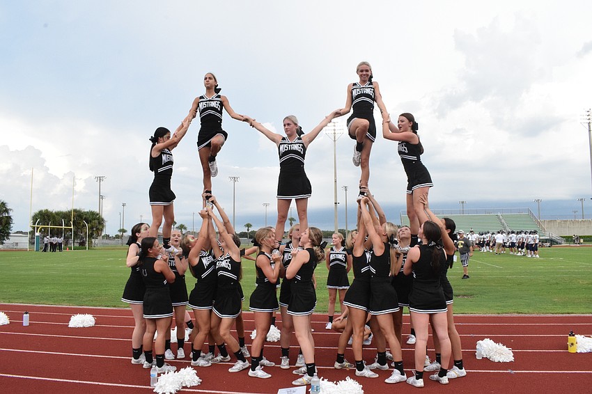 Lakewood Ranch High School cheerleaders work together to hold their flyers into the air for a stunt.