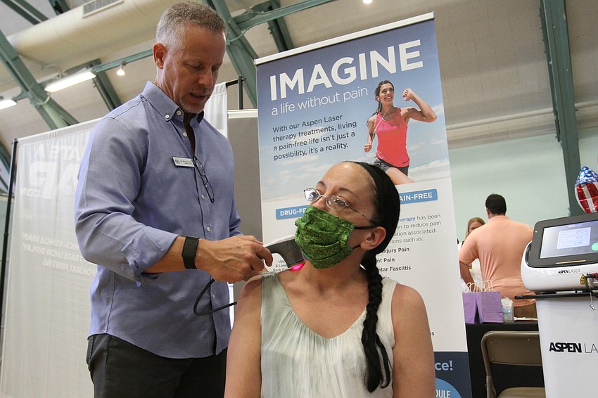 Ken Kaufman of Sarasota Sports Medicine  demonstrates what his business does with Mindy Dobzynski.