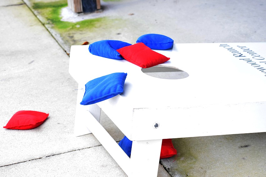 A blue bag slides off the cornhole board.