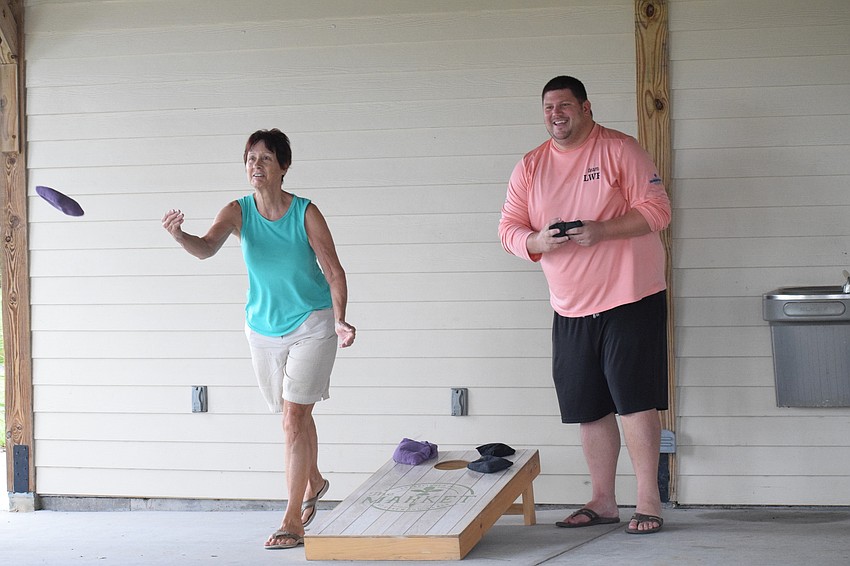 Lakewood Ranch's Mollie Saia throws a cornhole bag while Chris McComas with Lakewood Ranch Community Activities prepares for his turn.