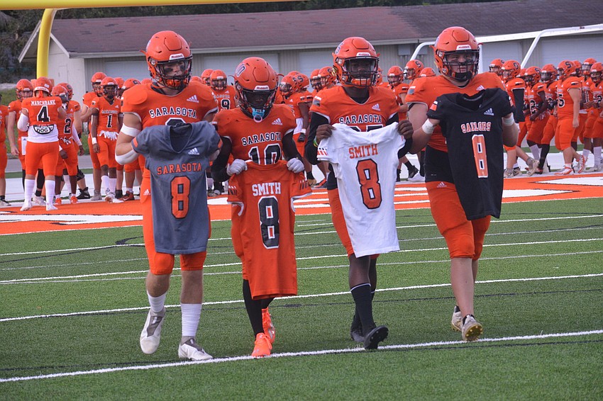 Ashton Turner, T.J. McKay, Jarmel Holloway and Branson Bordones walk all variations of former Sailors player Jalen Smith's jersey onto the field. Smith, 18, died in an accident at Nathan Benderson Park in July.