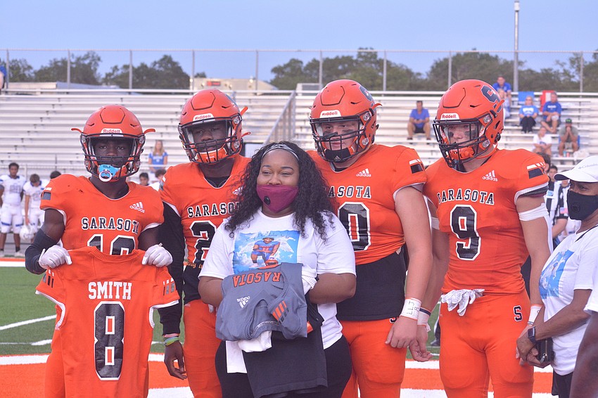 T.J. McKay, Jarmel Holloway, Branson Bordones and Ashton Turner present Jalen Smith's jerseys to Smith's mother, Saleemah Stanley. Smith's No. 8 jersey will be retired at the school.