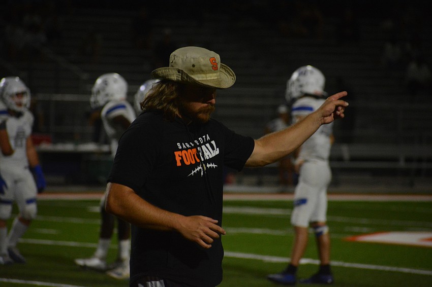 Sailors Coach Brody Wiseman, eyes covered by his hat's brim, signals to his team that a penalty is against Barron Collier.