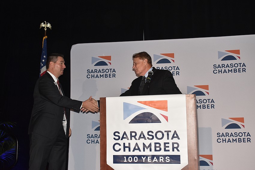 Larry Thompson, right, shakes hands with incoming chair Dennis Murphy as the transfer of chair occurs.