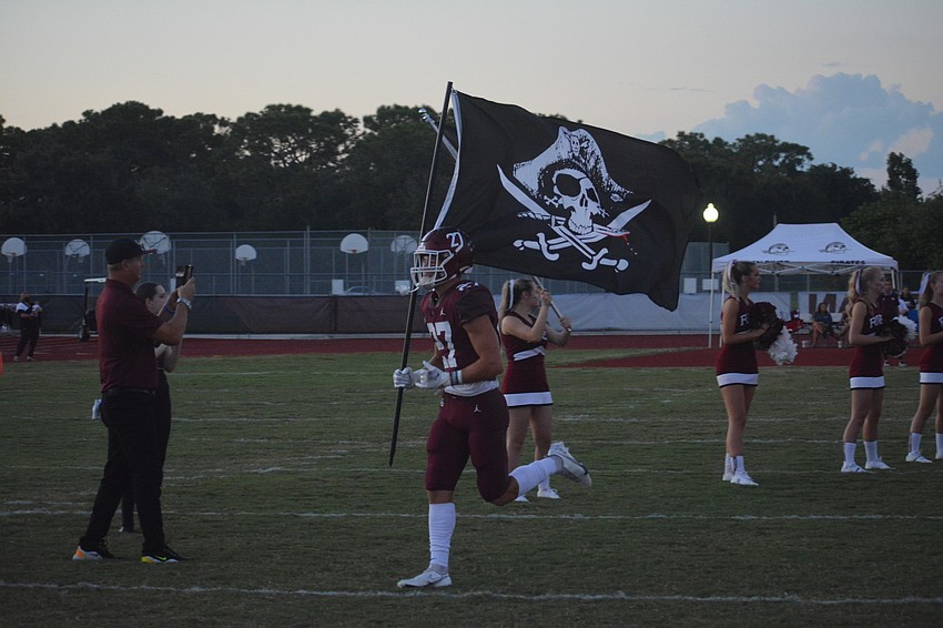 Braden River senior Dawson Thompson leads the team onto the field carrying the Pirates flag.
