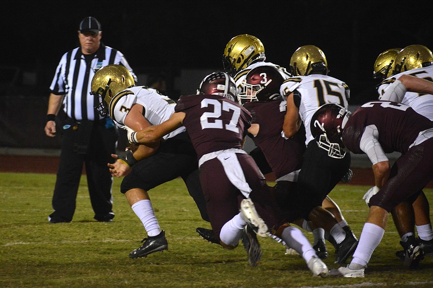 Pirates senior Dawson Thompson (27) brings down Bishop Moore quarterback Riley Willis.