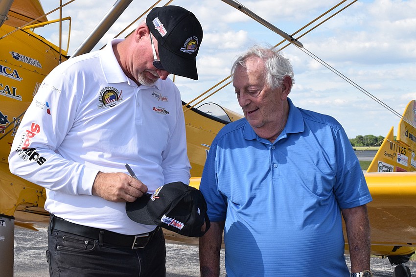 Darryl Fisher, the founder, president and pilot for Dream Flights, signs a Dream Flights hat for Joe Abrams, a Cypress Springs Gracious Retirement Living resident and Korean War veteran.