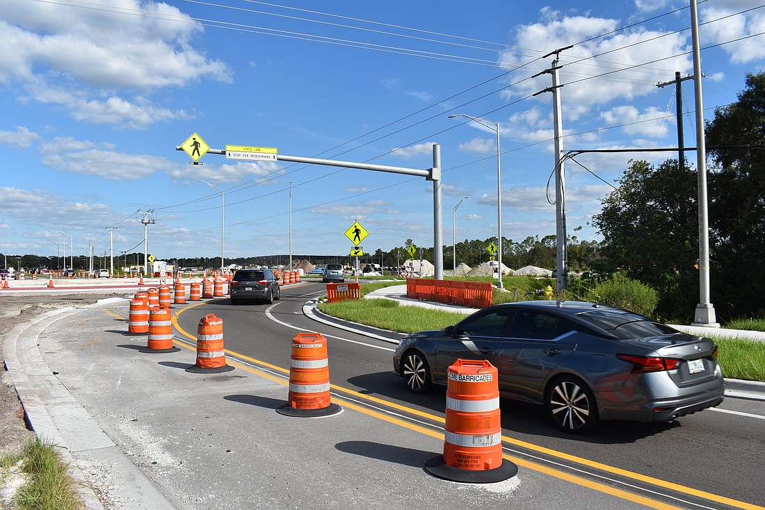 Motorists pass under the new pedestrian-activated lights at the roundabout under construction that will connect State Road 64, Grayhawk Blvd. and Pope Road in eastern Manatee County. Photo by Scott Lockwood.