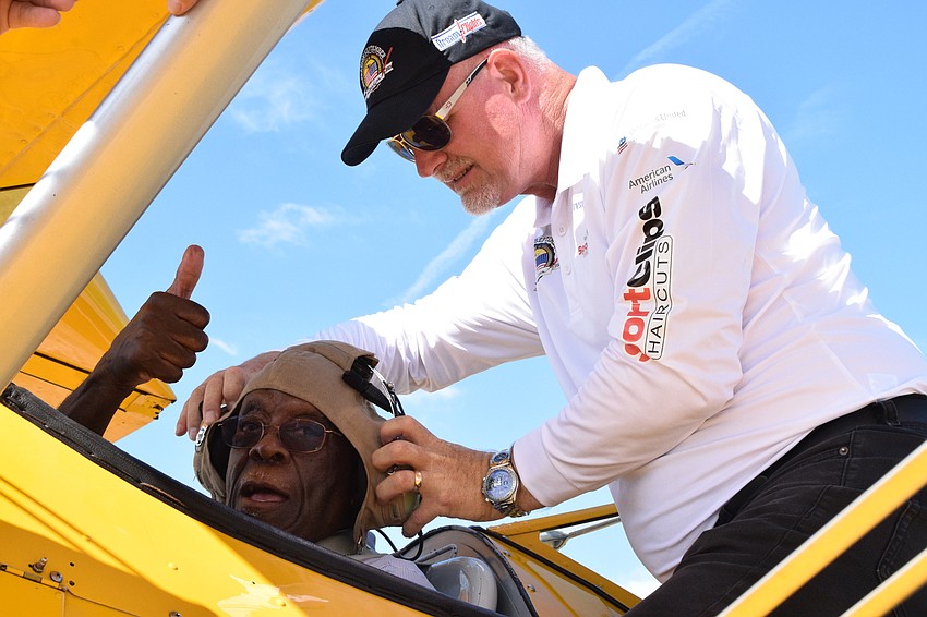 Melvin Pettis, a Cypress Springs Gracious Retirement Living resident and Navy veteran, gives a thumbs up as Darryl Fisher, the founder, president and pilot for Dream Flights, puts on a World War II pilot's helmet.
