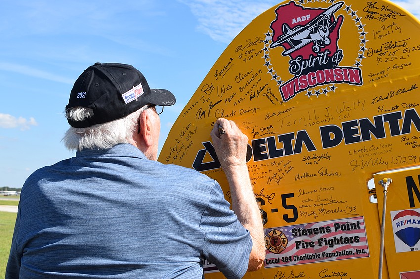 Chip Tominelli, a Cypress Springs Gracious Retirement Living resident and World War II veteran, signs the Spirit of Wisconsin.
