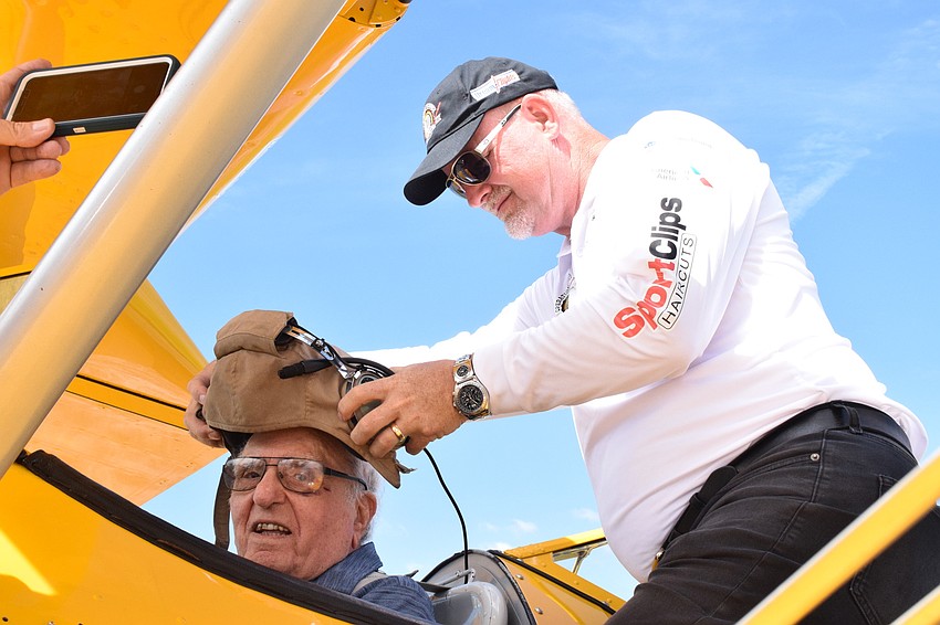 Chip Tominelli, a Cypress Springs Gracious Retirement Living resident and World War II veteran, smiles as Darryl Fisher, the founder, president and pilot for Dream Flights, puts a World War II pilot helmet on Tominelli.