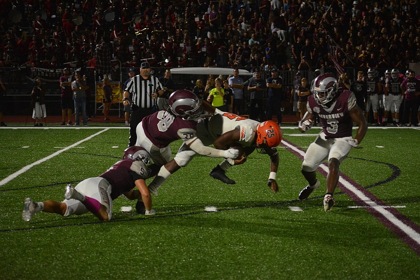 Sarasota running back Jarmel Holloway gets dragged down by Riverview's defense.