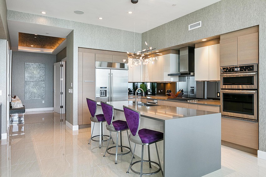 The fully-equipped modern luxury designed kitchen features a one-sided waterfall edge island with seating.