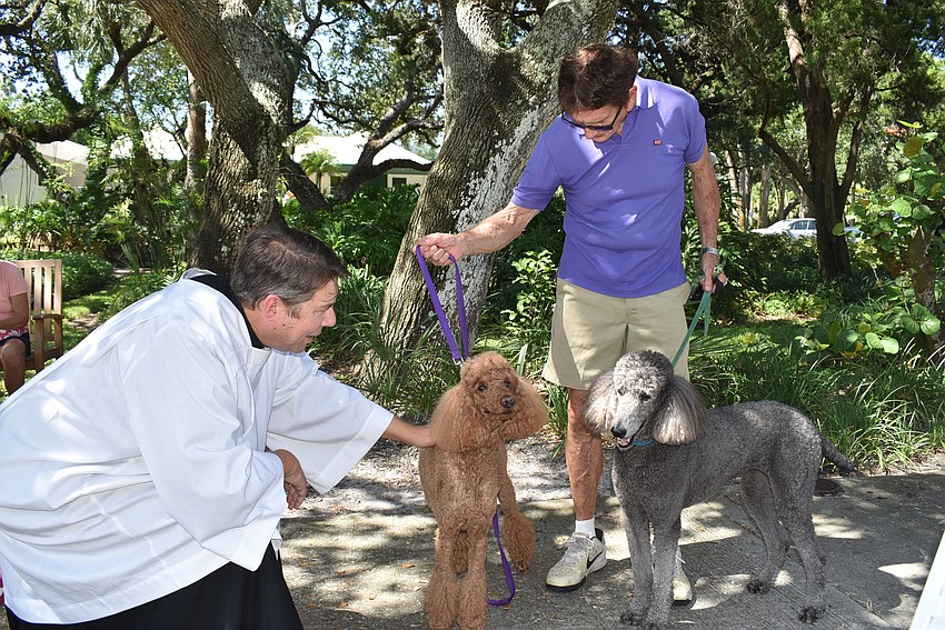 Dave Bishop, right holds the leashes of Chloe and Callie as Father Dave Marshall blesses them.